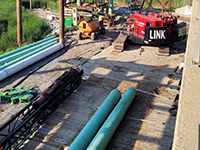 Downward angle of work site, construction equipment, and bridge support materials.